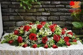 Dessus de cercueil composé d'un grand bouquet de roses rouges et de feuillage vert