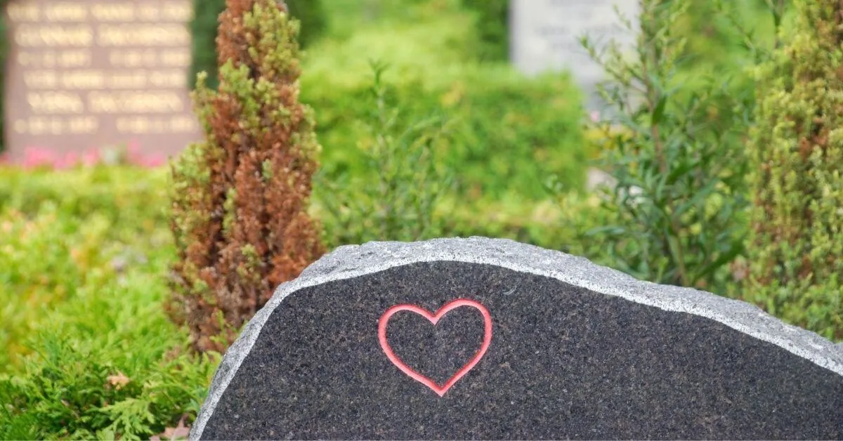 Pierre tombale en granit noir gravée d'un cœur rouge dans un jardin du souvenir